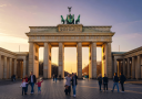 Berlin Brandenburg Gate iconic neoclassical monument illuminated at golden hour with tourists walking in foreground